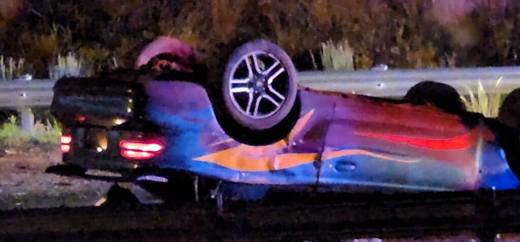 A green Mustang with multi-colored stripes is overturned on Clay at I-20. Photo by David Day
