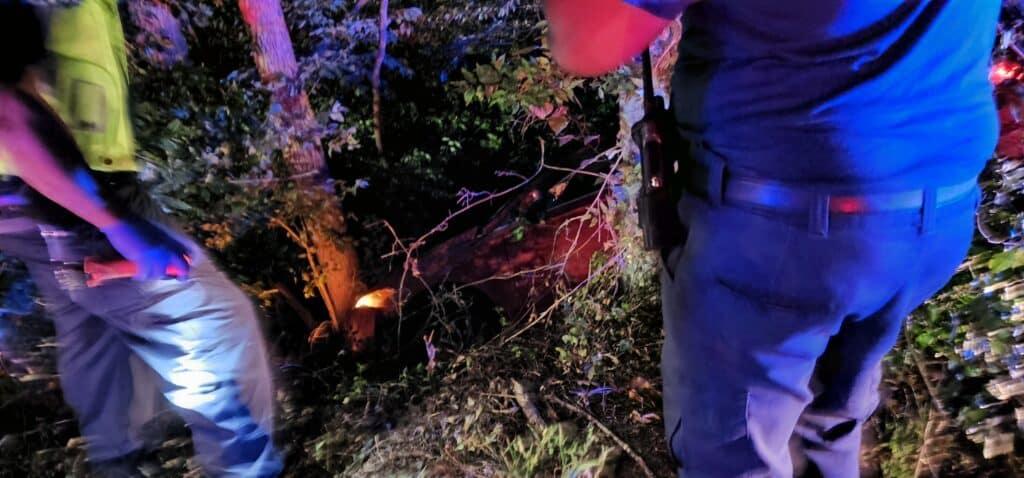 The red Ford Fusion in the ditch between two VFD first responders. Photo by David Day