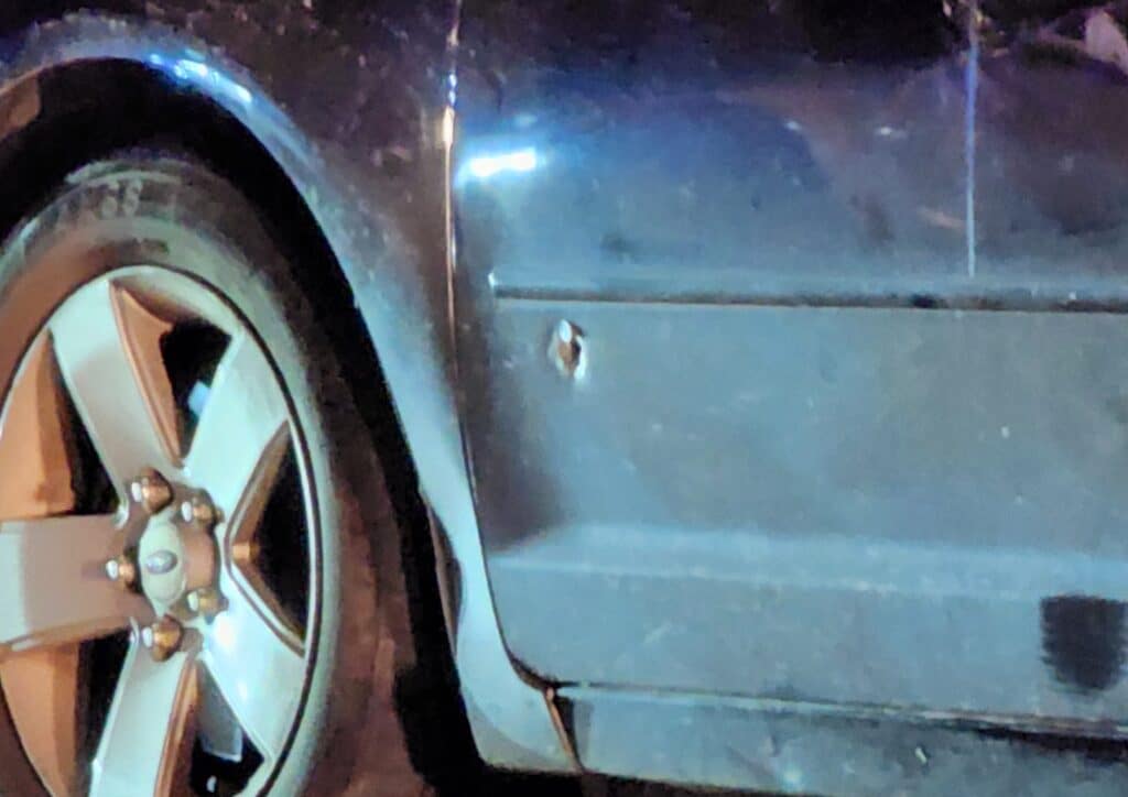 The black Ford sedan and what appears to be a bullet hole in the drivers door, but that has not yet been confirmed by law enforcement. Photo by David Day