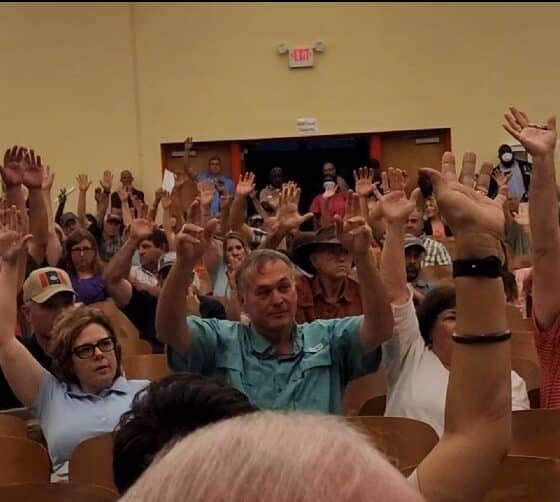 Everyone raised their hands when asked if they supported the pump project. Photo by David Day